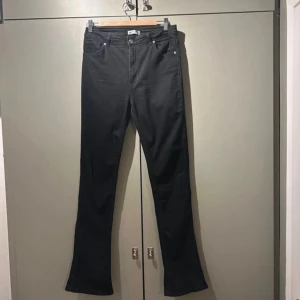 Svarta bootcut jeans från Gina Tricot - Säljer ett par svarta bootcut jeans från Gina Tricot i storlek 42. De är tillverkade av mer hållbar bomull och har en klassisk femficksdesign med knapp och dragkedja. Innerbenslängd 84 cm. Perfekta för både vardag och fest! 🖤