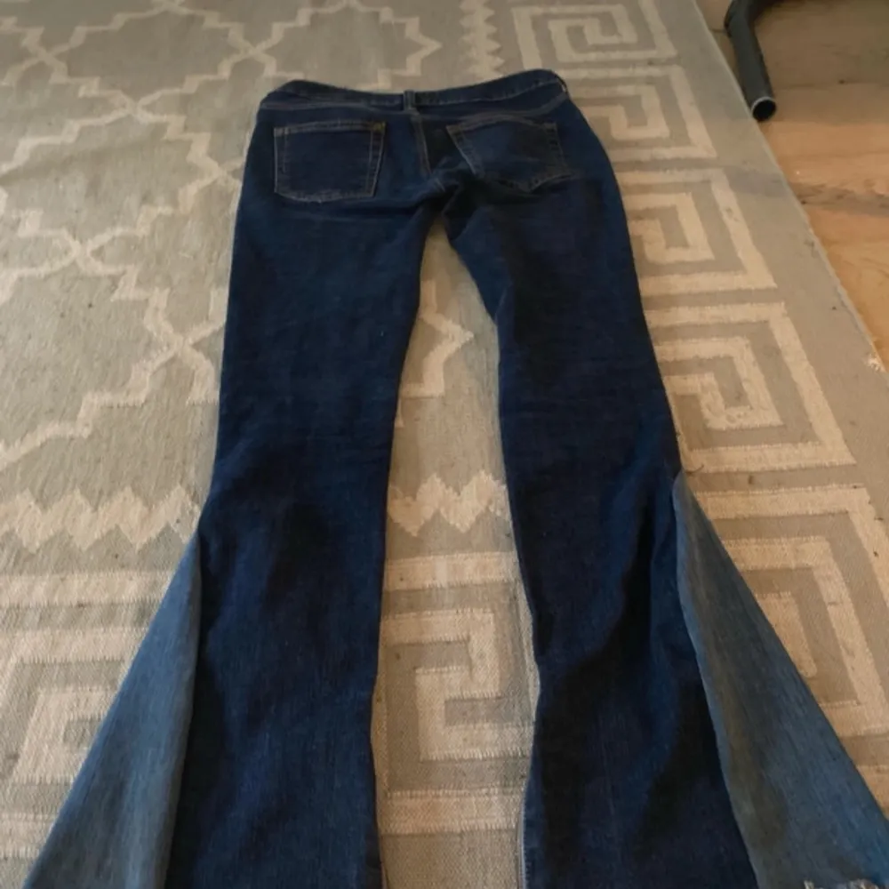 Säljer ett par snygga mörkblå bootcut jeans i bra skick. De är lågmidjade och har en cool dragkedjedetalj vid bensluten. Perfekta för både vardag och fest! 🕺. Jeans & Byxor.