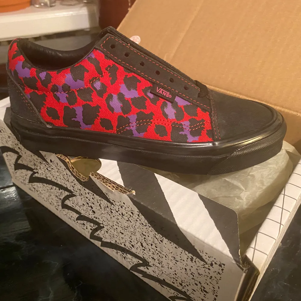 Säljer ett par coola Vans sneakers i svart med ett unikt rött och lila leopardmönster. Skorna är i mycket bra skick och perfekta för att ge din outfit en färgglad touch.. Kengät.