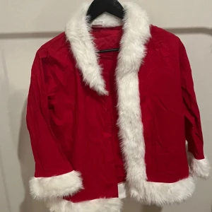 Röd juljacka med vit pälsdetalj - Säljer en superfin röd jacka perfekt för julen! Den har fluffiga vita pälsdetaljer runt kragen, ärmsluten och nederkanten. Jackan är långärmad och ger en mysig julkänsla. Perfekt för julfester eller bara för att mysa hemma. 🎅🎄