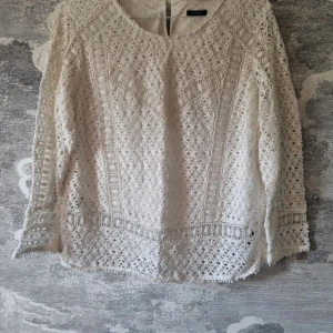 Vit spetsblus - Säljer en superfin vit spetsblus i 100% bomull. Den har ett vackert blommigt mönster och långa ärmar. Blusen är fodrad och känns både luftig och elegant. Passar både till vardags och festliga tillfällen. 