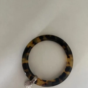 Leopardmönstrat armband med silverdetalj - Ti sento. Säljer ett snyggt leopardmönstrat armband med en liten silverdetalj. Armbandet har en cool och trendig design som passar perfekt till både vardag och fest. Det är i mycket bra skick och mäter cirka 7 cm i diameter. Perfekt accessoar för att ge din outfit det där lilla extra! 🐆✨