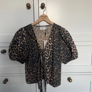 Leopardmönstrad blus från Neo Noir - Snygg leopardmönstrad blus från Neo Noir i storlek 36. Blusen har korta puffärmar och knytband framtill för en chic look. Perfekt för både vardag och fest! 🐆✨. Helt ny och köpt för 599