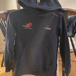 Mörkblå hoodie från Alinghi Red Bull Racing - Säljer en snygg och bekväm mörkblå hoodie från sail racing. Den har en känguruficka framtill och en justerbar huva. Perfekt för alla racingfans! 🏎️