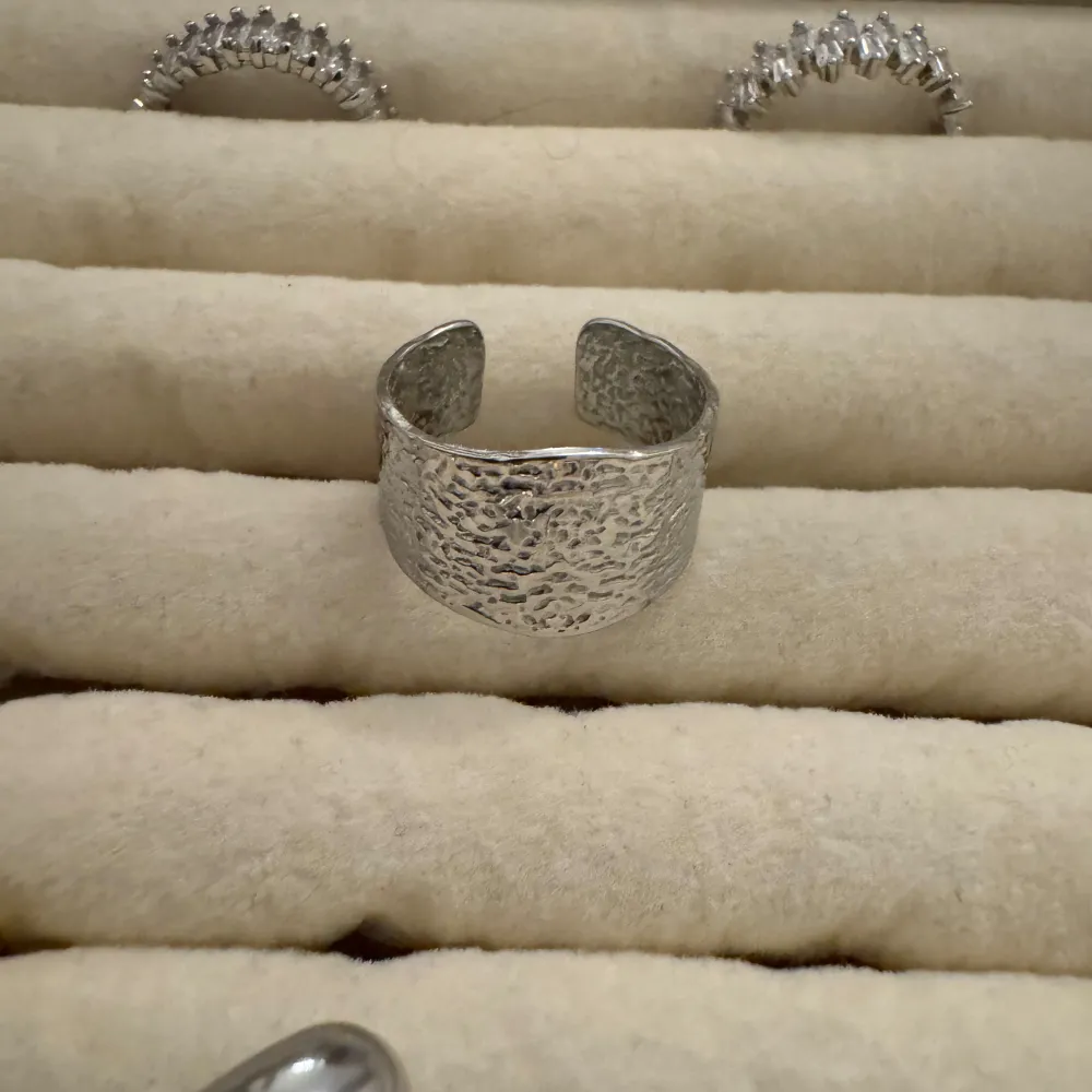 Säljer en cool och unik silverfärgad ring med en grov textur. Ringen har en öppen design vilket gör den justerbar och bekväm att bära. Perfekt för att ge en edgy touch till din outfit!. Accessoarer.