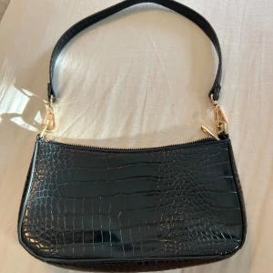 Axelväska  - En svart liten axelväska med ett innerfack. 