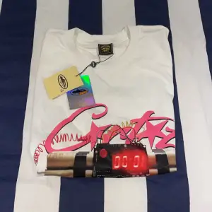 Säljer en vit t-shirt med ett coolt tryck på framsidan som föreställer en röd digital display och rosa stjärnor. På baksidan står det 'NO TIME 4 LUV' i stora svarta bokstäver. Perfekt för en avslappnad stil!