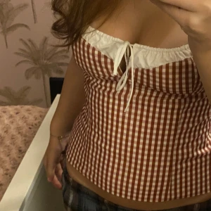 Rutig korsettopp med knytband - Säljer denna populära  korsettopp från Zara. Toppen har en söt knytning framtill, den är ärmlös och har en tight passform som framhäver figuren. Perfekt för fest eller en dag på stan!💞💞många intresserade av denna så högst bud!