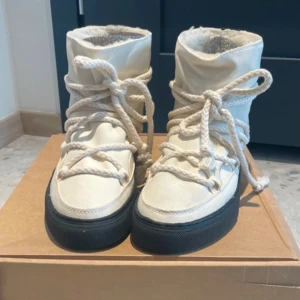 Beige boots från INUIKII - Säljer ett par snygga och varma beige boots från INUIKII. De har en hög modell med snörning och en svart sula. Perfekta för kalla dagar med sitt mjuka och fodrade inre. Skorna är i nyskick och kommer i originalförpackning. 