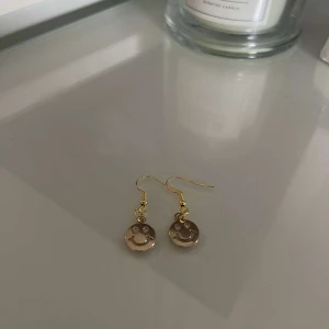 Guldörhängen med smiley - Säljer ett par supercoola guldörhängen med smiley-motiv. De är perfekta för att liva upp vilken outfit som helst och ger en glad touch till din stil. Passar både till vardags och fest!
