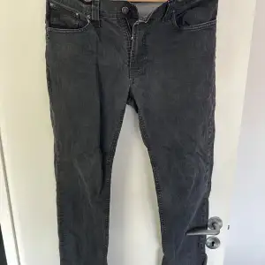 Säljer ett par svarta jeansbyxor från nudie jeans i bra skick. De har en klassisk femficksdesign med dragkedja och knapp framtill. Perfekta för vardagsbruk eller en avslappnad kväll ute.