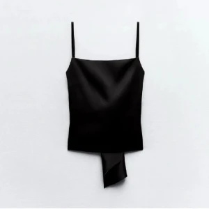 Zara satin topp - Elegant svart axelbandslös topp i silkes liknande material med öppen rygg och knytning. Använd några gånger, köpt i somras. Några trådar här och där men ingen större defekt. Storlek xs