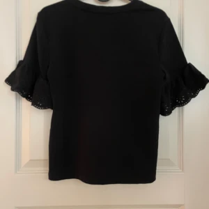 Svart topp med volangärmar - Snygg svart topp med volangärmar som ger en trendig look. Perfekt för att piffa upp din outfit. Passar bra till både jeans och kjol.