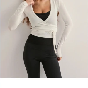 Vit omlottopp - Snygg vit omlottopp med långa ärmar och knytning i midjan. Perfekt för en stilren och modern look. Passar bra till både jeans och kjol.
