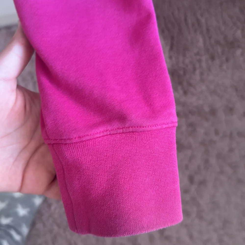 Säljer en rosa hoodie från Nike med deras klassiska logga i vitt på framsidan. Hoodien har en stor ficka framtill och justerbar huva med dragsko. Perfekt för en avslappnad stil.. Neuletakit & Villapaidat.
