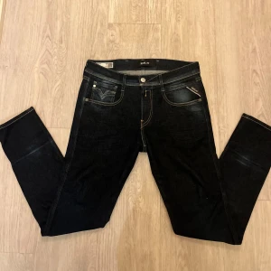 Mörkblå jeans från Replay - Snygga mörkblå jeans från Replay i modellen Anbass. De har en slim fit passform och är tillverkade av återvunnet material. Klassisk design med fem fickor och knappgylf. Perfekta för en stilren look.