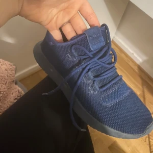 Adidas skor  - Snygga blå sneakers från Adidas med stickad ovandel och klassisk snörning. Perfekta för en avslappnad stil. Märkeslogga synlig på tungan och hälen.