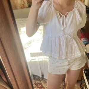 Vit blus från Gina Tricot - Säljer en söt vit blus från Gina Tricot med korta ärmar och volangdetaljer. Blusen har en knytning framtill och en luftig passform, perfekt för varma dagar. Den är gjord i ett lätt och bekvämt material. Toppen är verkligen perfekt inför sommaren och passar till långa & korta kjolar🤩🤩☝🏼SLUTSÅLD I BUTIK & ONLINE