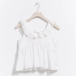 Vit ärmlös blus med volangdetaljer - Säljer en söt vit blus från Gina Young  med volangdetaljer runt halsen och knytband i nacken. Blusen är ärmlös och har en luftig passform💓 skriv om du vill ha fler bilder eller undrar över något💞