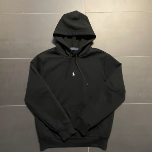 Svart hoodie från Polo Ralph Lauren - Säljer en stilren svart hoodie från Polo Ralph Lauren med det klassiska broderade logotypen på bröstet. Tröjan har en bekväm passform med långa ärmar och en praktisk magficka. Ny pris: ca 2250kr Vårt pris: 999kr. Skick:9,5/10 tröjan har varit använd ett fåtal gånger. Det är bara att kontakta vid minsta fråga 😁
