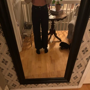 Svarta byxor - Snygga svarta byxor med hög midja och bootcut-stil. Perfekta för en stilren look. Byxorna har en klassisk design med knappar och dragkedja framtill.