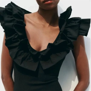 Svart body med volangdetaljer - Trendig svart body med v-ringning och stora volangdetaljer runt axlar och hals. Slutsåld på Zaras hemsida.