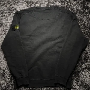 Svart sweatshirt från Stone Island - Säljer en stilren svart sweatshirt från Stone Island med deras ikoniska märke på ärmen. Tröjan har långa ärmar och en rund halsringning. Perfekt för en casual look. Skick 9/10.  Kan diskuteras pris i dm|tröjan är i XL men passar perfekt som en L|