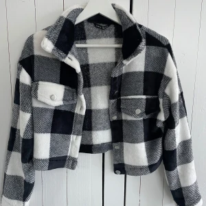 Svartvit rutig jacka från Shein - Säljer en snygg svartvit rutig jacka från Shein. Jackan är croppad med knappar framtill och har två bröstfickor med knappar. Perfekt för en enkel men uppkläd stil