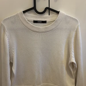 Vit stickad tröja från Bikbok - Väldigt stilren stickad tröja ifrån bikbok med många fina detaljer som gör den till ”lite extra” den har slit vid ärmanrna och även ribbat matrial, och även slit och ribbat matrial längst ned av tröjan.