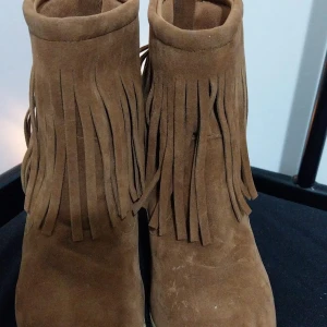 Bruna mocka boots med fransar - Snygga bruna boots i mocka med fransdetaljer och dragkedja baktill. Perfekta för en bohemisk stil och passar bra till höstgarderoben.