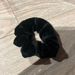 Svart sammet scrunchie - Snygg svart scrunchie i mjukt sammetstyg. Perfekt för att ge en elegant touch till din frisyr. Passar bra för både vardag och speciella tillfällen.