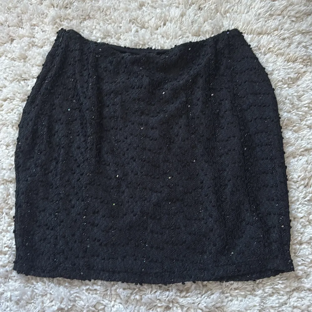 Snygg svart minikjol med glittrande detaljer och en liten slits framtill. Kjolen har en dragkedja på sidan. Från NA-KD, aldrig använd ✨ . Hameet.