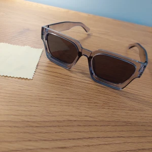 Solglasögon från Only Fashion - Snygga solglasögon med transparent båge och mörka rektangulära linser. Perfekta för en stilren look. Kommer med en praktisk förvaringspåse. Perfekt till sommaren för att se grisch ut.