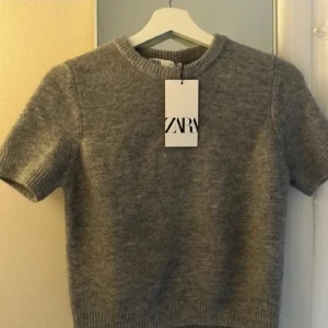 Zara stickad kortärmad grå tröja 💕 - Säljer en stilren grå tröja från Zara. Den är i storlek S och är stretchig och väldigt mjuk. 💕 Passar perfekt till en modern outfit. 