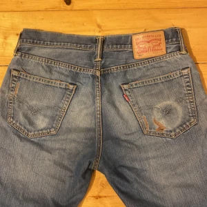 Blå Levi's jeans - Säljer ett par jätte coola mid waist raka blå Levi's 504 jeans med slitna detaljer. W32 L34. Jag är 168 för referens och de är lite långa på mig. Skriv vid frågor!💕