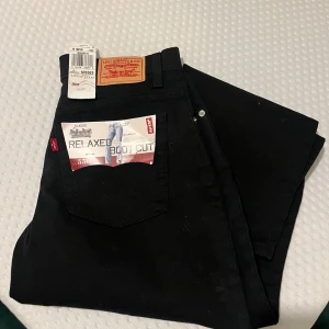 Svarta Levis 550 jeans - Säljer ett par svarta Levis 550 jeans med relaxed fit och bootcut-stil. Dessa jeans har en klassisk design med en bekväm passform. Perfekta för en avslappnad look.