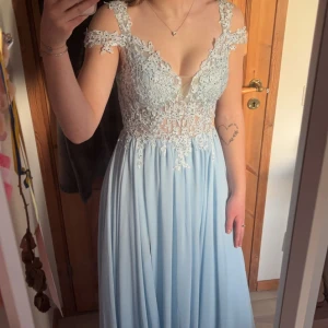 Balklänning  - Säljer nu min fina balklänning, ljusblå med fina detaljer och slits vid vänstra benet. Köpt på Hebeos för ca 1400kr💕 Storlek S och går ner till marken på mig som är 168cm💖Använd endast under en dag!