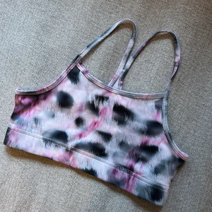 Mönstrad sporttopp från SOC - Säljer en snygg sporttopp från SOC med ett unikt mönster i rosa, svart och vitt. Toppen har smala axelband och är perfekt för träning. Materialet är mjukt och stretchigt för bästa komfort.