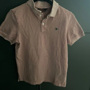 Rosa pikétröja från Morris - Säljer en stilren rosa pikétröja från Morris i storlek XS. Tröjan har korta ärmar och klassisk krage med knappar framtill. Perfekt för en avslappnad men ändå snygg look. 