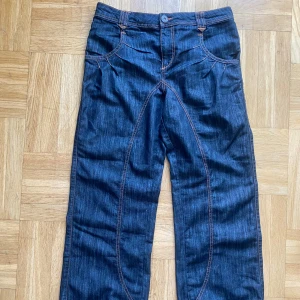 Mörkblå jeans från ONLY - Snygga mörkblå jeansbyxor från ONLY med orange kontrastsömmar och unika detaljer på bakfickorna. 