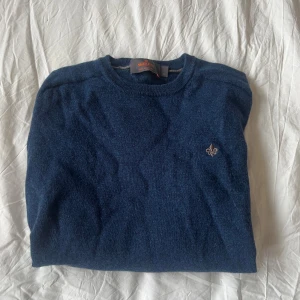 Mörkblå stickad tröja från Morris - Säljer denna stilrena tröjan från Morris😍 Den är mörkblå med ett broderat emblem på bröstet. Tröjan har långa ärmar och är tillverkad i merinoull. Den är i storlek S och har inga defekter.                                            Hör gärna av er vid intresse eller frågor💞💞
