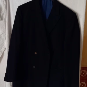 Mörkblå kavaj från Sir Man of Town - Elegant mörkblå kavaj från Sir Man of Town. Kavajen har en klassisk design med två knappar på vardera sidor och en stilren passform. Perfekt för formella tillfällen.