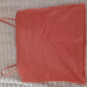Orange linnetopp från Gina Tricot - Säljer en snygg orange/rosa topp från Gina Tricot med smala axelband. Axelbanden är uppsydda för att förkorta dem men går enkelt att förlänga igen. 