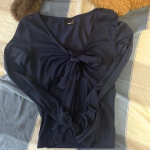 Mörkblå tröja med knyt från Gina Tricot - Snygg mörkblå tröja från Gina Tricot med knyt framtill. Tröjan har långa ärmar och en v-ringad design som ger en elegant look. Perfekt för en stilren outfit.