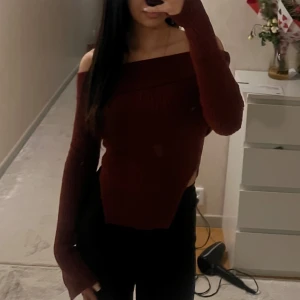 Vinröd offshoulder tröja - Säljer en snygg vinröd offshoulder tröja med ribbad design. Tröjan har långa ärmar och en bekväm passform som passar perfekt för höst och vinter. Perfekt för att hålla stilen både inne och ute.