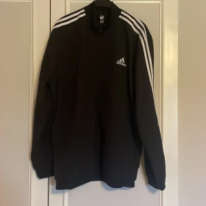 Svart långärmad tröja från Adidas - Säljer en svart långärmad tröja från Adidas med klassiska vita ränder på axlarna. 