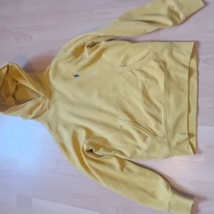 Gul hoodie från Ralph Lauren - Säljer en snygg gul hoodie från Ralph Lauren med en klassisk känguruficka och broderad logga på bröstet. Perfekt för en avslappnad stil. Passar bra till både jeans och joggers. Hör av dig vid intresse! 💛