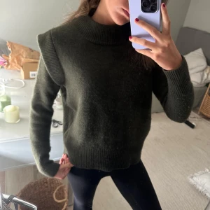 Mörkgrön stickad tröja - Säljer en mysig mörkgrön stickad tröja med ribbade detaljer vid hals, ärmslut och nederkant. Perfekt för kyliga dagar och ger en stilren look. Passar bra till både jeans och leggings. 100% Kashmir 