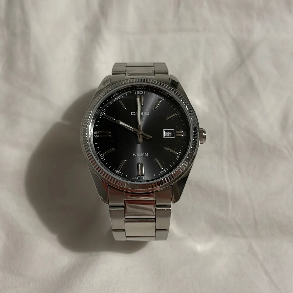 Snygg och stilren klocka från Casio med svart urtavla och datumvisning. Klockan har en silverfärgad länkarmband och en boett i rostfritt stål. Perfekt för dig som gillar en klassisk look med modern touch.. Asusteet.
