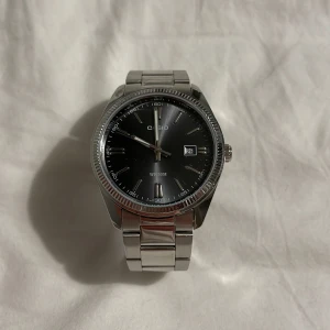 Silverfärgad klocka från Casio - Snygg och stilren klocka från Casio med svart urtavla och datumvisning. Klockan har en silverfärgad länkarmband och en boett i rostfritt stål. Perfekt för dig som gillar en klassisk look med modern touch.